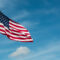 American Flag against the backdrop of a blue sky and clouds.