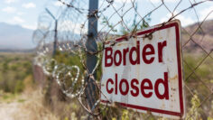Grungy border closed warning sign on fence with barbed wire with copy space for text. Concept of illegal immigration control and security