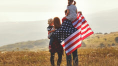 happy family with flag of america USA at sunset outdoors