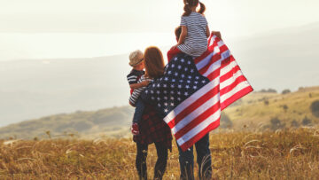 happy family with flag of america USA at sunset outdoors