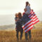 happy family with flag of america USA at sunset outdoors