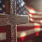 Wooden cross with American flag in soft church lighting.