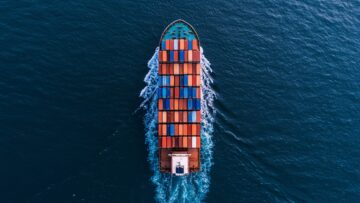 Wide aerial drone shot of container ship complying with IMO Push Green Shipping regulations sailing with zero visible emissions.