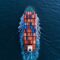 Wide aerial drone shot of container ship complying with IMO Push Green Shipping regulations sailing with zero visible emissions.