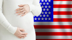 Beautiful pregnant woman belly against American flag background. Demographics and pregnancy in USA concept
