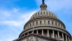 low angle view of American flag on United States Capitol building Washington DC with marble dome and blue sky in background