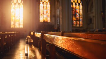 Wooden pews bathed in warm sunlight inside a serene church, colorful stained glass windows casting patterns,