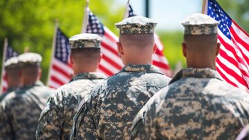 Salute to Service: A poignant image of soldiers standing in formation, their backs turned, holding American flags in a solemn and respectful tribute to their service and sacrifice.