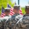 Salute to Service: A poignant image of soldiers standing in formation, their backs turned, holding American flags in a solemn and respectful tribute to their service and sacrifice.