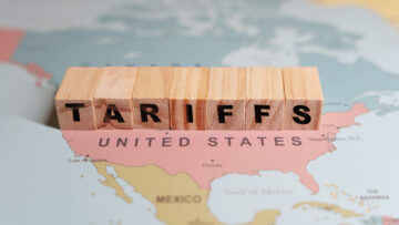 Wooden blocks spelling TARIFFS are placed on a map of North America, specifically over the United States and Mexico