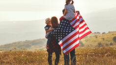 happy family with flag of america USA at sunset outdoors