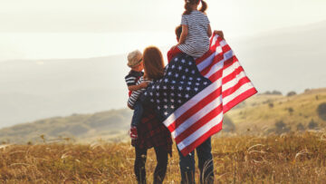 happy family with flag of america USA at sunset outdoors