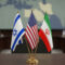 Flags of Israel, United States, and Iran displayed on a table during a diplomatic meeting in a conference room setting, concept of peace agreements, diplomacy, Middle East conflict