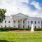The White House on a summer day with the American flying over it.