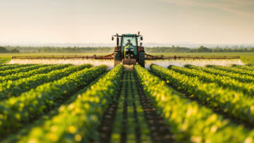 Tractor spraying pesticides on soybean field