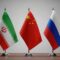 Flags of iran, china, and russia on small flagpoles on a table