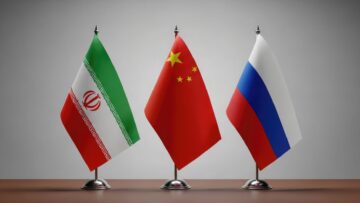 Flags of iran, china, and russia on small flagpoles on a table