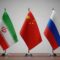 Flags of iran, china, and russia on small flagpoles on a table