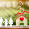 Woman hand hold family with paper cut and home model red arrow graph with growing value and money drop with working capital management in the public park, Saving money for future investment concept.