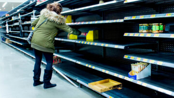 Woman grabbing product of of thinly stocked shelves at a supermarket during the Coronavirus Pandemic