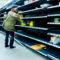 Woman grabbing product of of thinly stocked shelves at a supermarket during the Coronavirus Pandemic