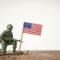 Memorial Day with a green toy soldier and American flag on a white background, national day concept with copy space for text