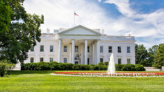 The White House on a summer day with the American flying over it.